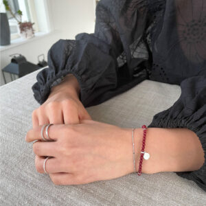 Stilrent armband med små pärlor i djupröd imiterad cinnabarsten och platinapläterade 925 sterling silver detaljer, designat av svenska Livingstone Wikh Accessories.